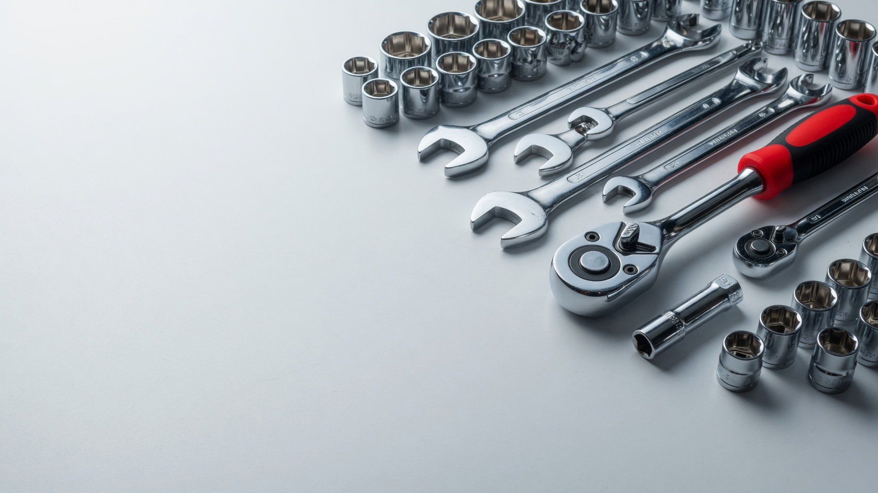 Drop-forged wrenches and sockets on a light studio surface